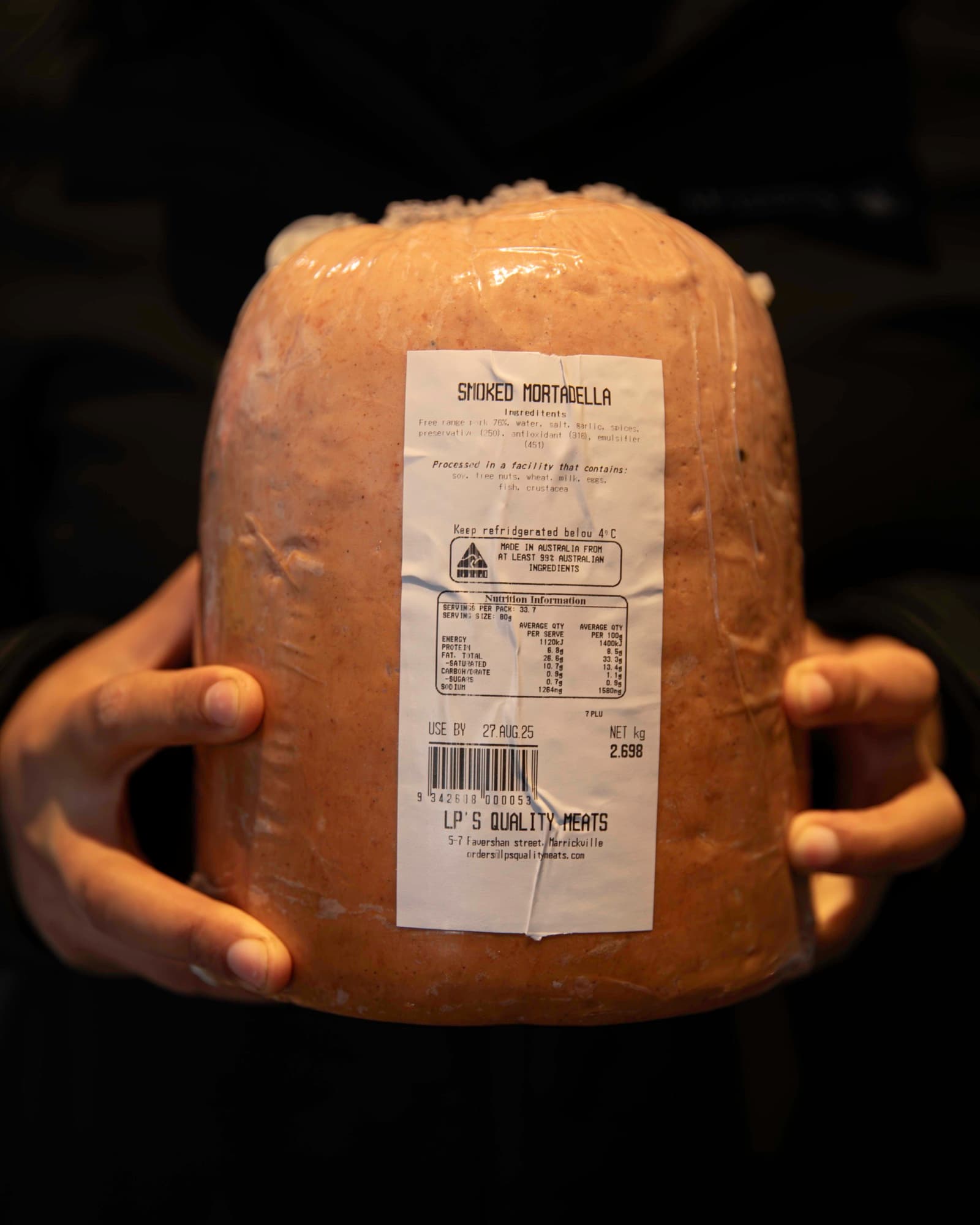 Two kilos of smoked mortadella from LP's Quality Meats in Marrickville, held in hands ready for the slicer