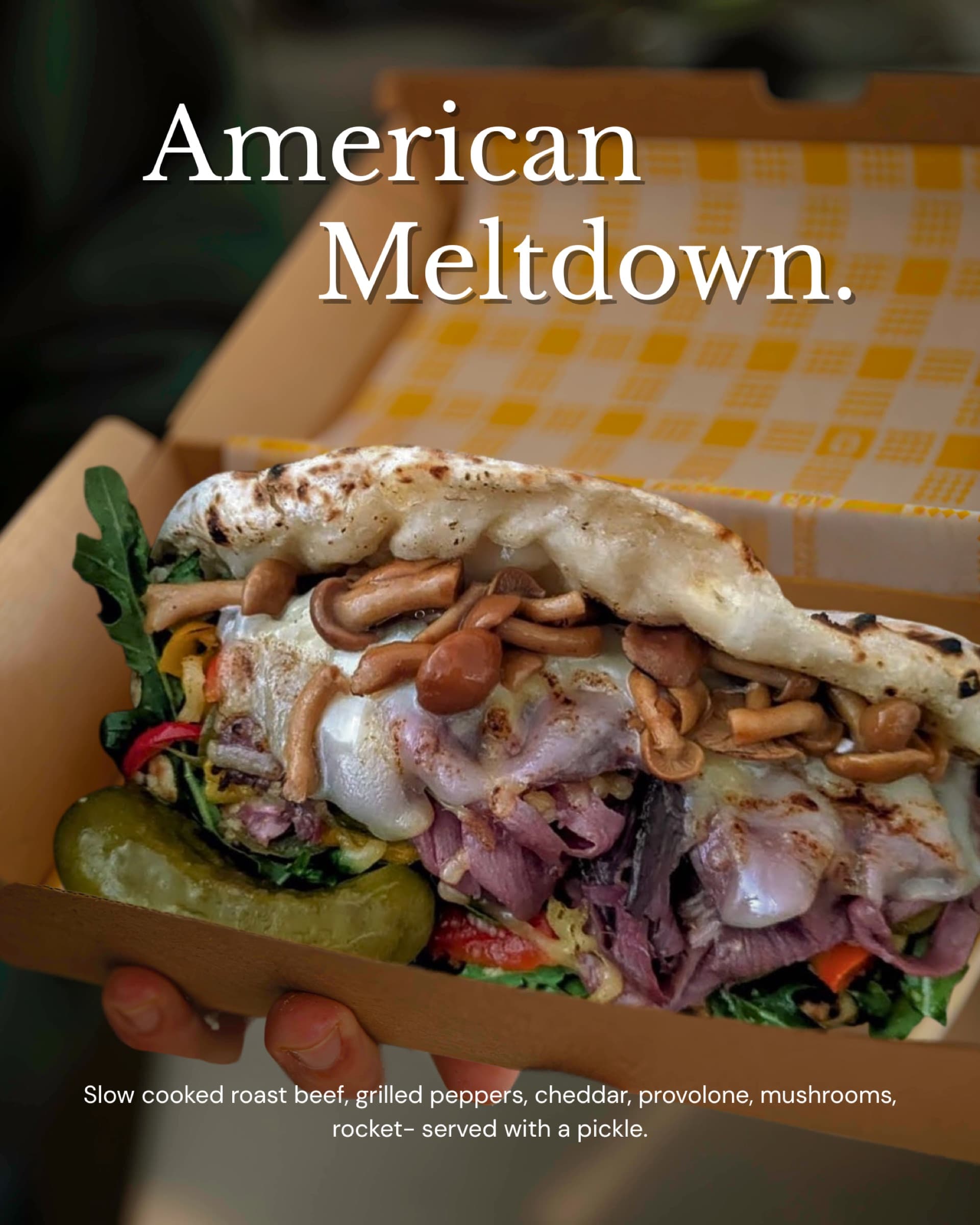 American Meltdown ozzo in a yellow-check box — slow-cooked roast beef, grilled peppers, cheddar, provolone, mushrooms, rocket, pickle